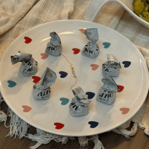 Prato para bolo porcelana redondo branco com corações pintados de diversas cores e a inscrição "amor" no centro.