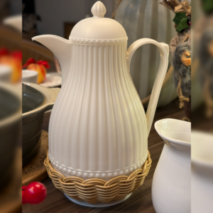 Garrafa Térmica em rattan e poliestiereno na cor branca em cima de uma mesa posta.